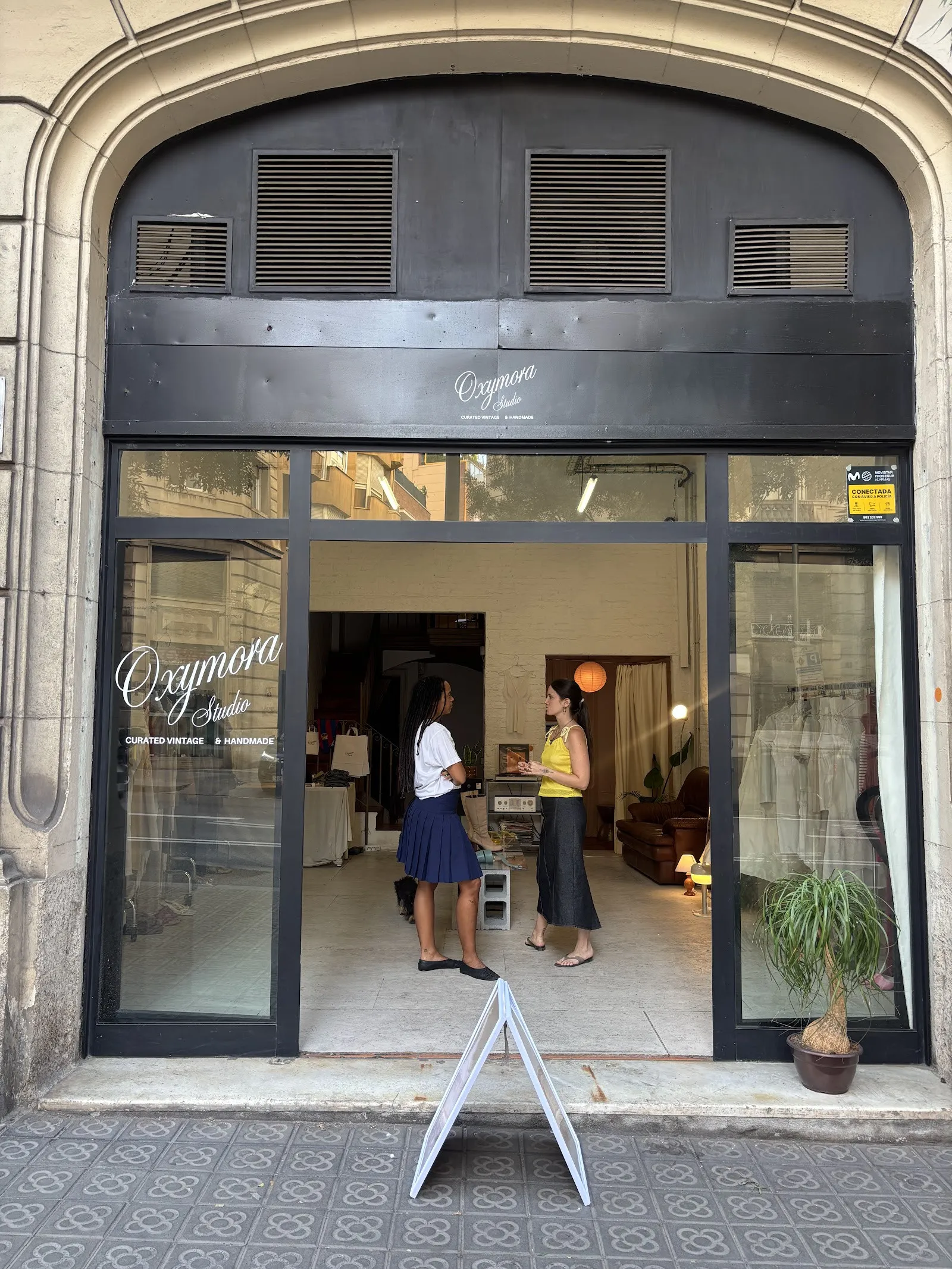 L'entrada d'Oxymora Studio a la Riera de Cassoles, amb la porta de vidre oberta i dues persones a dins